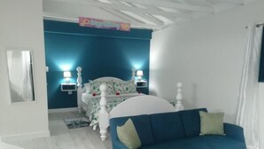 Un dormitorio con cama, sofá azul y mesita de noche con lámparas.