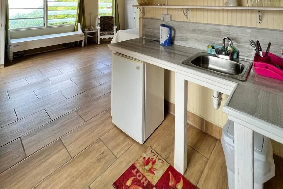 A compact kitchen with a wooden ceiling, a built-in sink, and a small refrigerator.