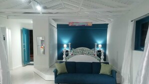 Un dormitorio con una cama, un sofá azul y una mesita de noche con dos lámparas.