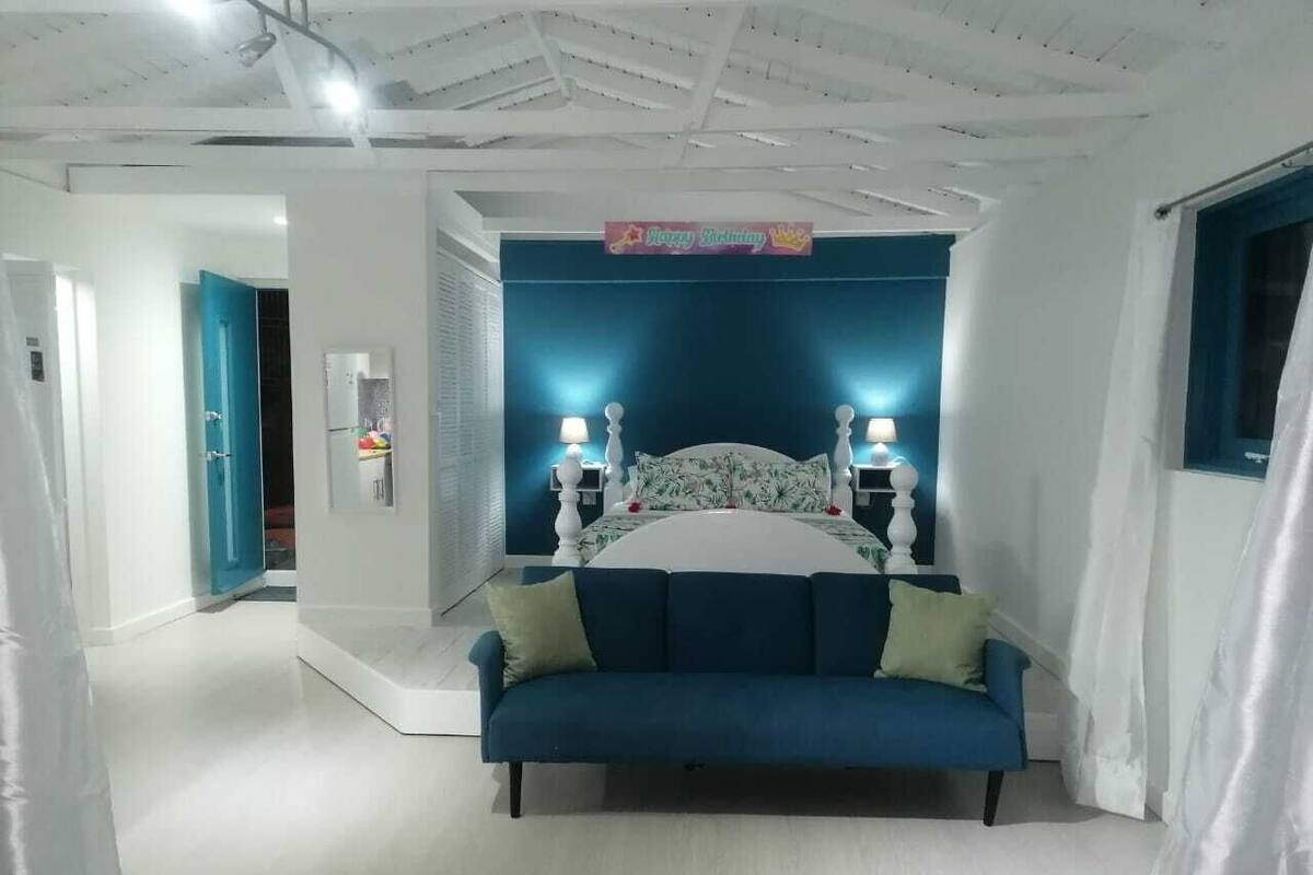 A bedroom with a bed, a blue sofa, and a nightstand with two lamps.