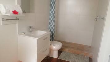A small, clean bathroom with a white sink, toilet, and shower.