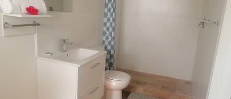 A small, clean bathroom with a white sink, toilet, and shower.