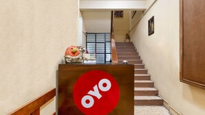 A reception desk with a red logo, a staircase, and a wall-mounted painting. - Hotel Esperanza Oaxaca Centro (Oaxaca)