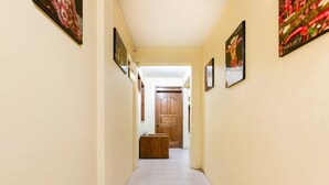 A narrow hallway with light yellow walls and tiled flooring, leading to a wooden door at the end. - Hotel Esperanza Oaxaca Centro (Oaxaca)