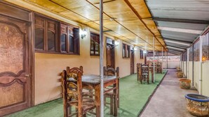 A covered corridor with wooden doors and chairs, green carpet, and potted plants. - Hotel Esperanza Oaxaca Centro (Oaxaca)