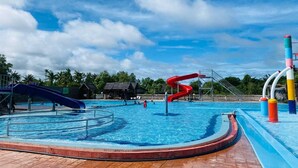 A swimming pool with two slides and a water play area.