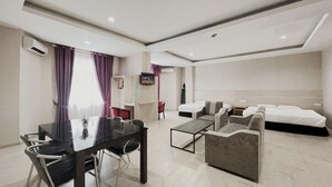Een moderne hotelkamer met een eethoek, een televisie, een bed en een bank.