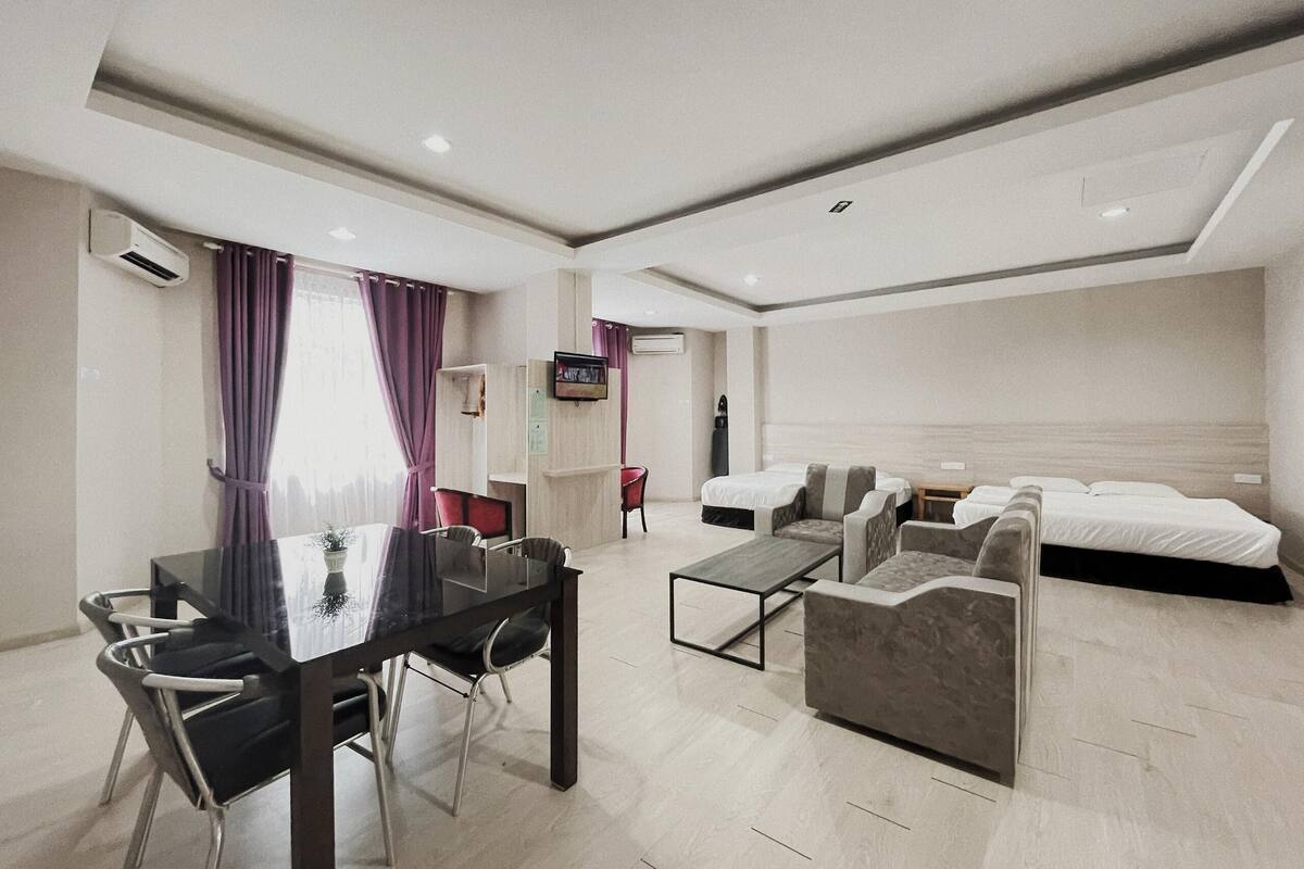 Une chambre d’hôtel moderne comprenant un coin repas, une télévision, un lit et un canapé.