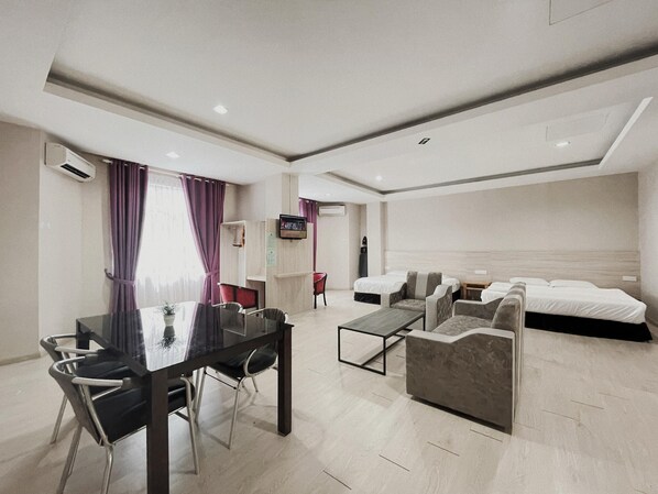 A modern hotel room with a dining area, a TV, a bed, and a sofa.