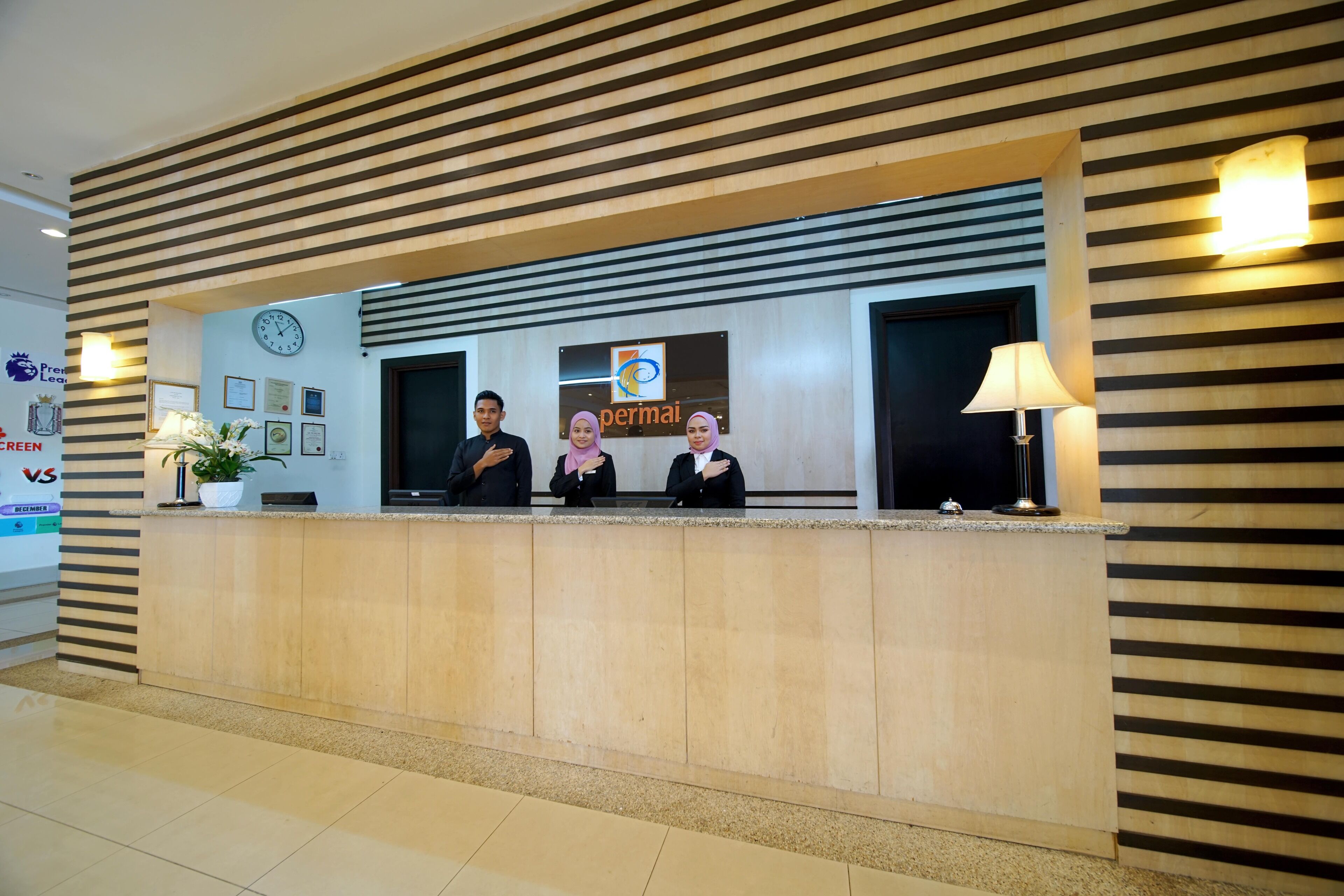 A reception desk with a clock, framed certificates, and a logo.