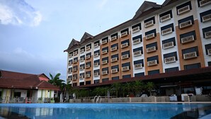 Un hotel con piscina, varios balcones y tejado de tejas rojas.
