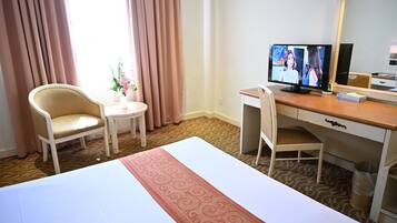 A hotel room with a bed, a desk, a chair, a television, and a mirror.
