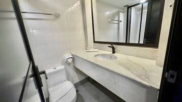 Un baño moderno con inodoro, lavamanos y espejo.