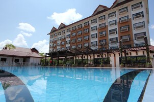 Un hotel con piscina, varios balcones y un cielo azul despejado.