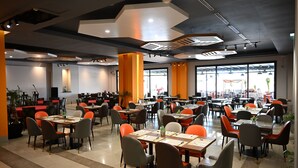 Un comedor amplio con múltiples mesas y sillas, ventanas grandes y un diseño moderno en el techo.