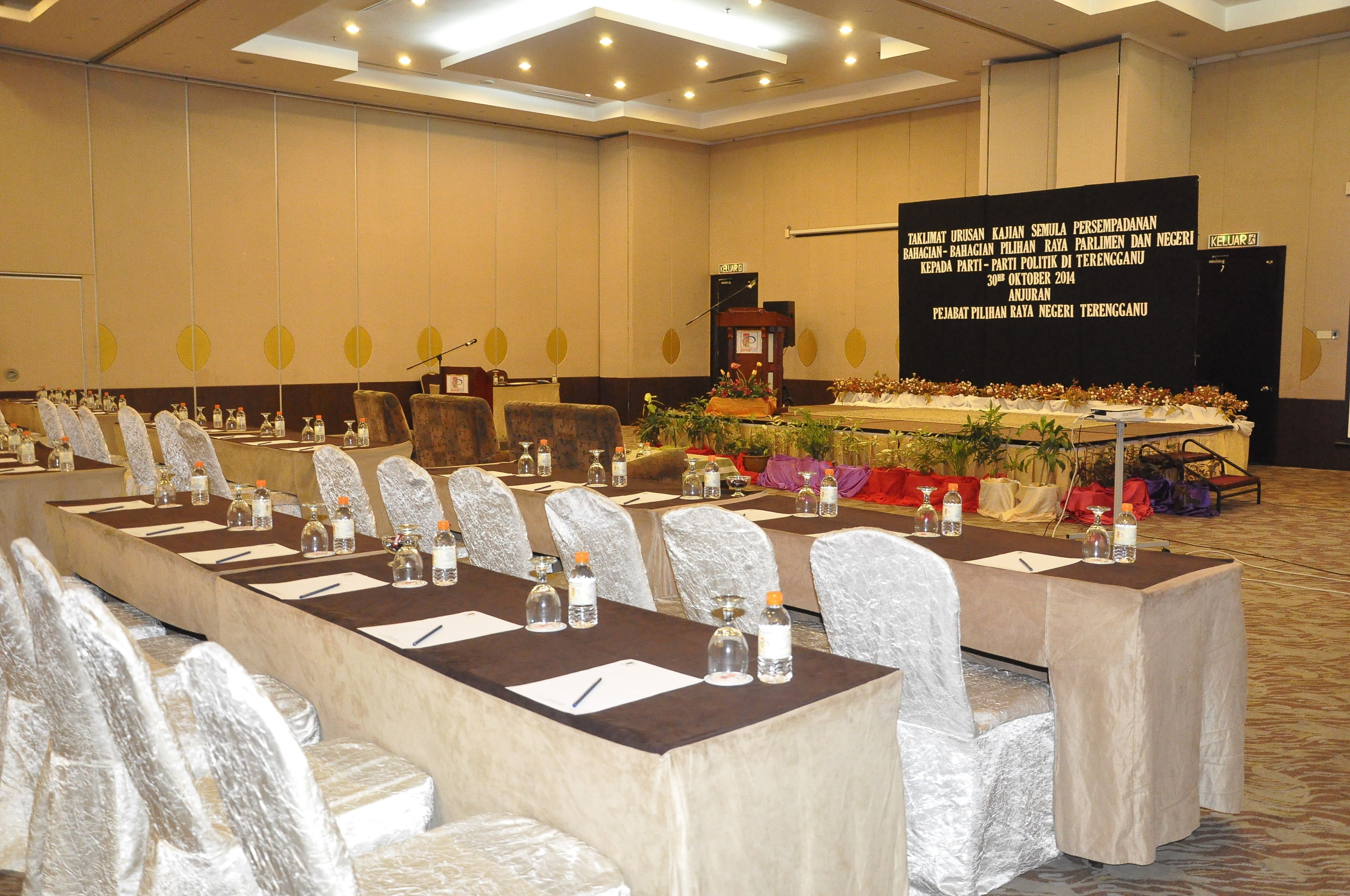 A conference room with a long table, chairs, and a stage with a podium.