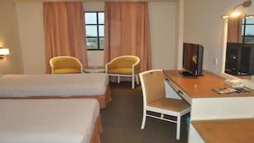 Una habitación de hotel con dos camas, un escritorio con televisor y una silla.