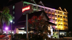 Un hotel de varios pisos con un cartel rojo llamativo, balcones e iluminación destacada en la fachada.
