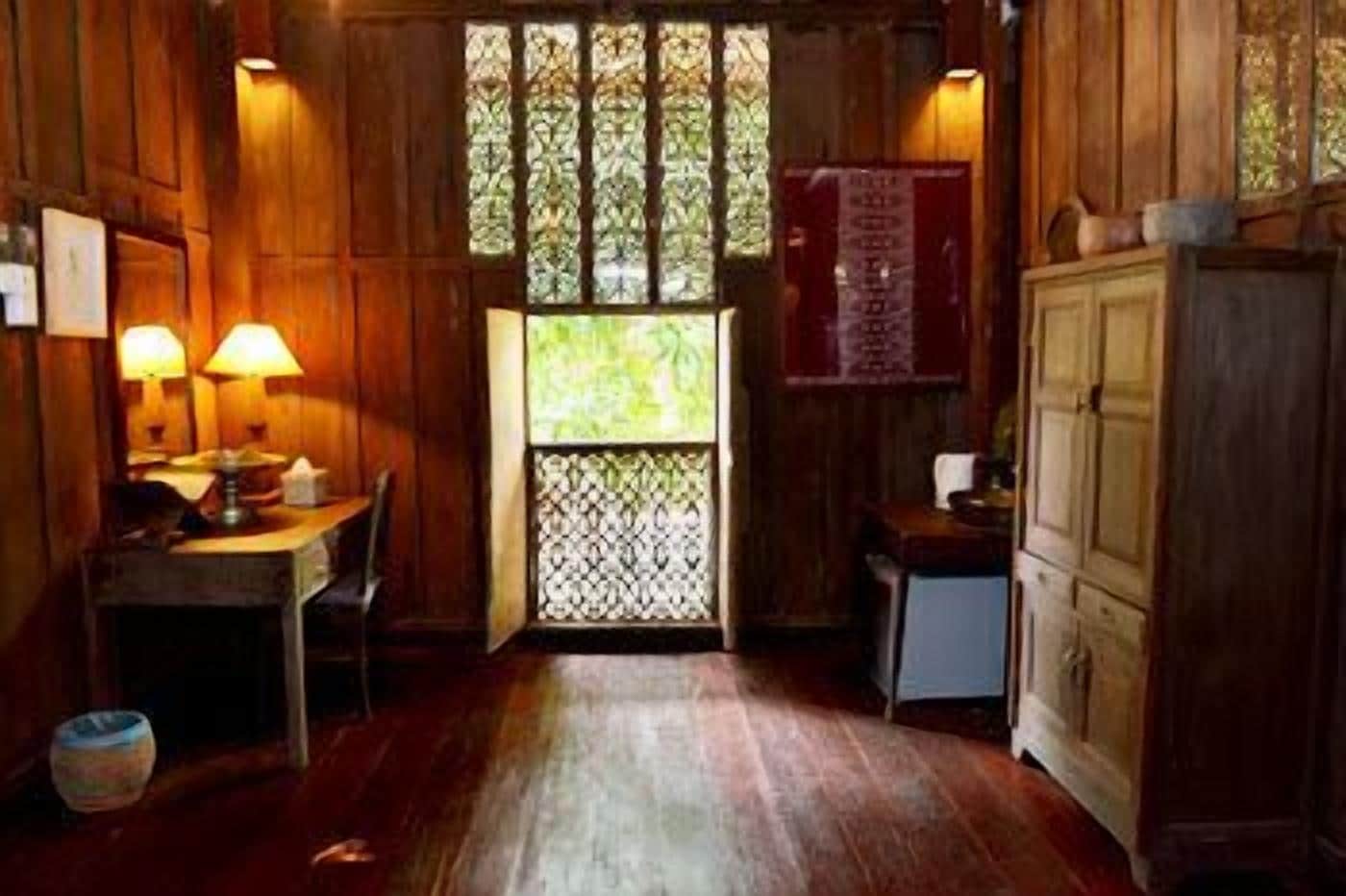 Une pièce en bois avec une table et des chaises, une fenêtre ornée d’un paravent décoratif et un meuble.