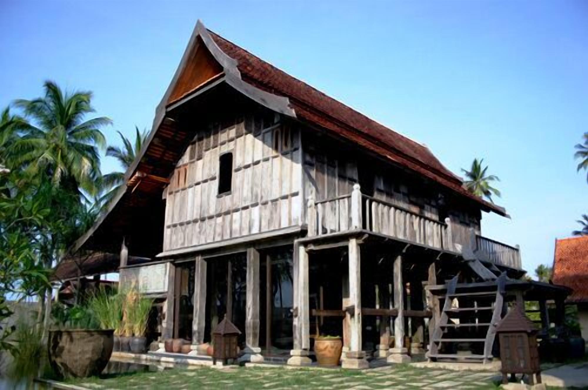 Uma casa de madeira tradicional com telhado inclinado, várias janelas e varanda com colunas.