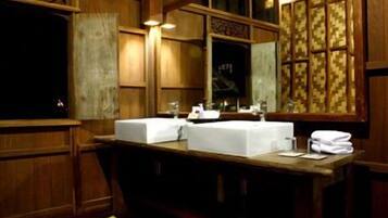 A wooden bathroom with two sinks, a mirror, and a window with patterned curtains.