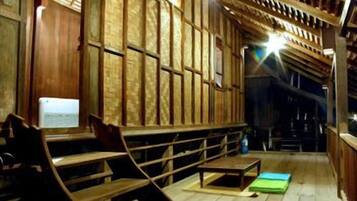 Un intérieur en bois avec des bancs et une table, une fenêtre donnant sur un paysage agréable et un plafond avec des poutres en bois.