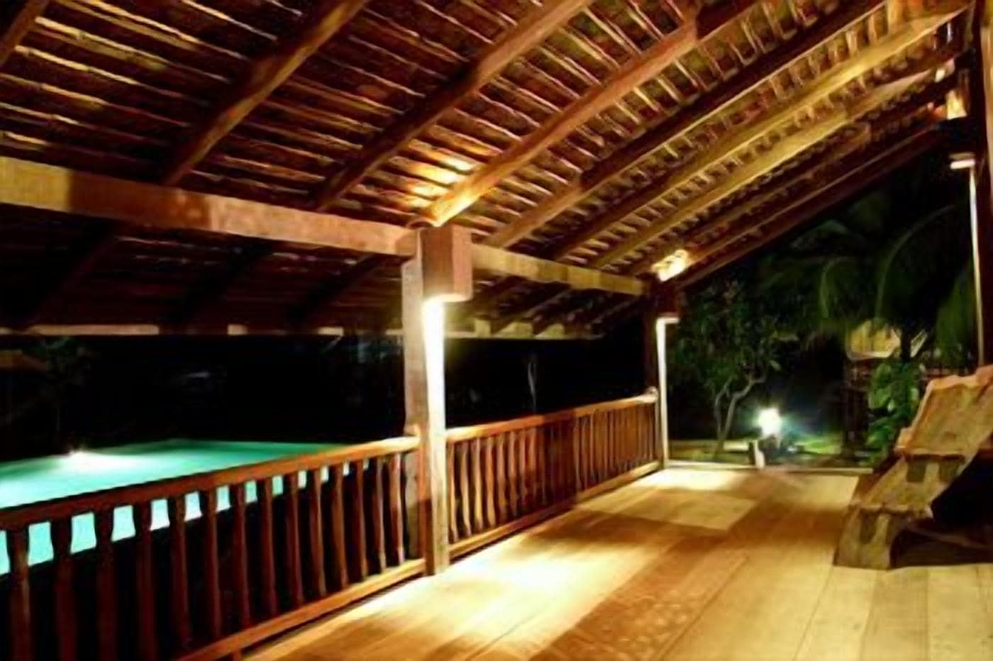Un espace extérieur abrité comprenant une piscine, une terrasse en bois et un éclairage d’ambiance pour la nuit.