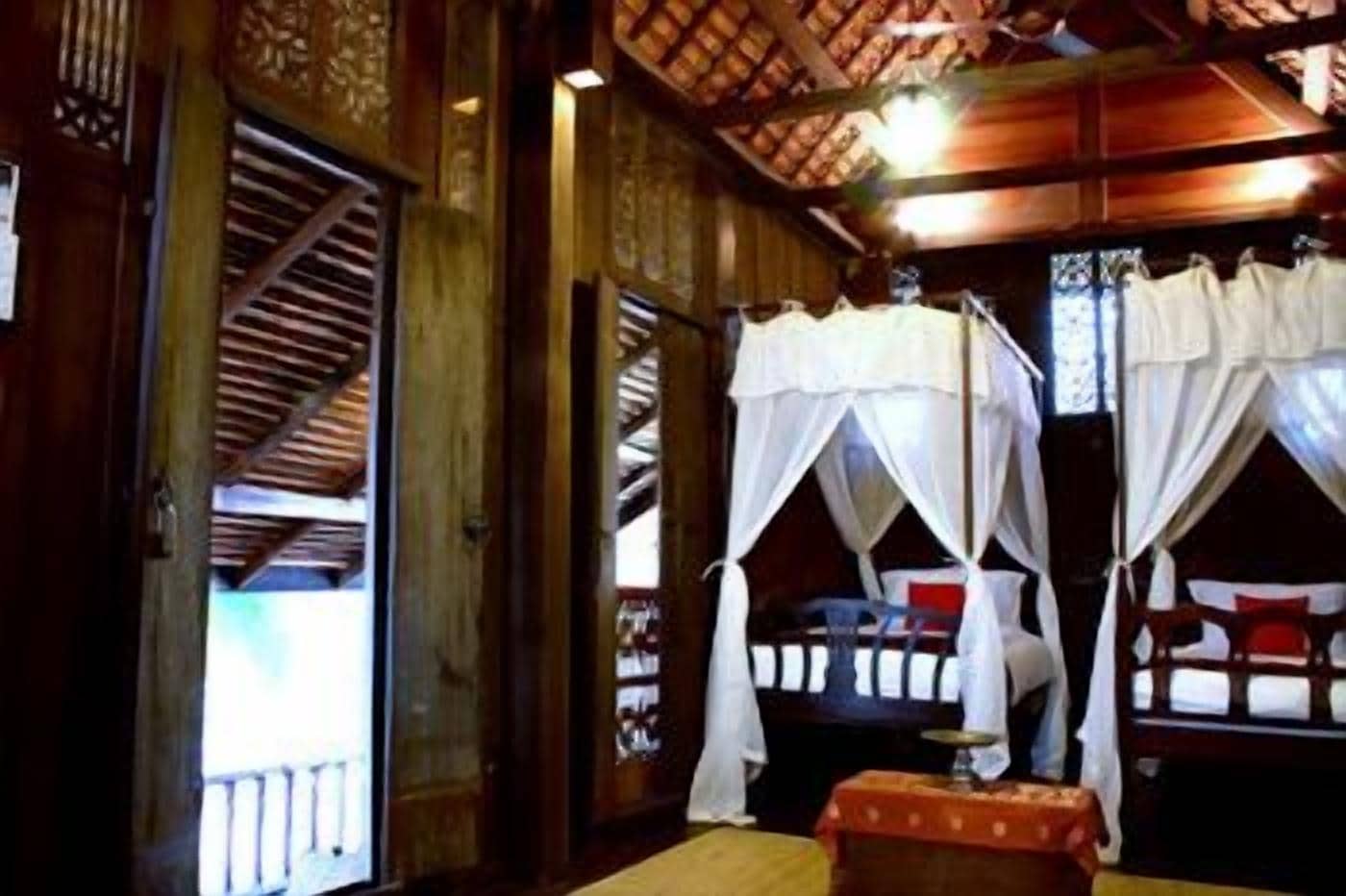 A traditional wooden room with two beds, each with a canopy.
