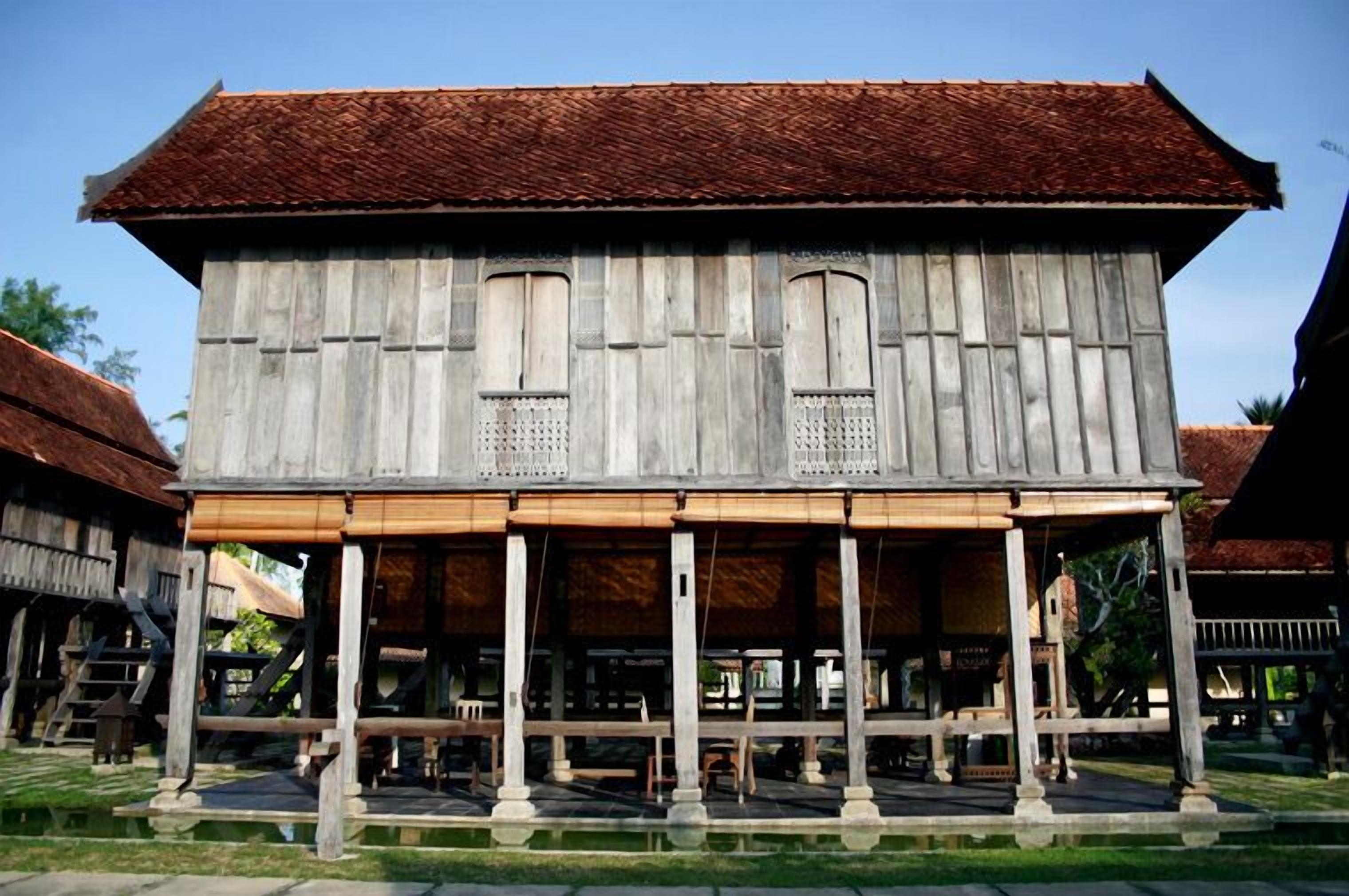 A traditional wooden building with a tiled roof, a covered porch, and a water feature in front.