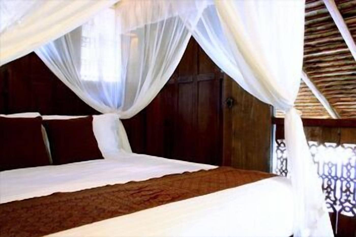 A bed with a canopy, wooden walls, and a decorative railing.