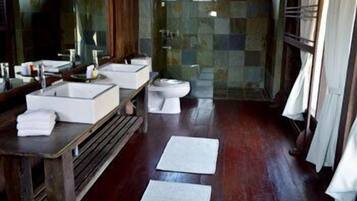 Un bagno con un mobile bagno in legno, due lavandini, un water e una zona doccia.