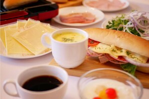 Un repas composé d’un sandwich, de fromage et d’une tasse de café, le tout posé sur une table.