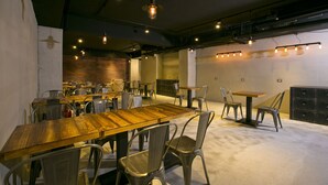 A spacious dining area with multiple tables and chairs, a brick wall, and hanging pendant lights. - York Design Hotel (Taipei)
