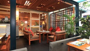 A cozy indoor seating area with wooden furniture and a checkered floor. - Ivory Hotel Bandung (Bandung)