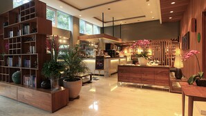 A spacious lobby with a large wooden bookshelf, a reception desk, and a coffee bar. - Ivory Hotel Bandung (Bandung)