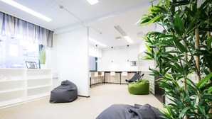 A modern office space with bean bags, a bookshelf, and a large plant. - Forenom Hostel Espoo Otaniemi (Espoo)