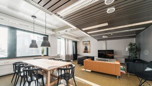 A modern office space with a large table, black chairs, a sofa, and a TV. - Forenom Hostel Espoo Otaniemi (Espoo)