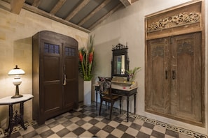 A checkered floor, a wooden wardrobe, a mirror, a table with a lamp, and a chair. - Kampung Kecil (Denpasar)