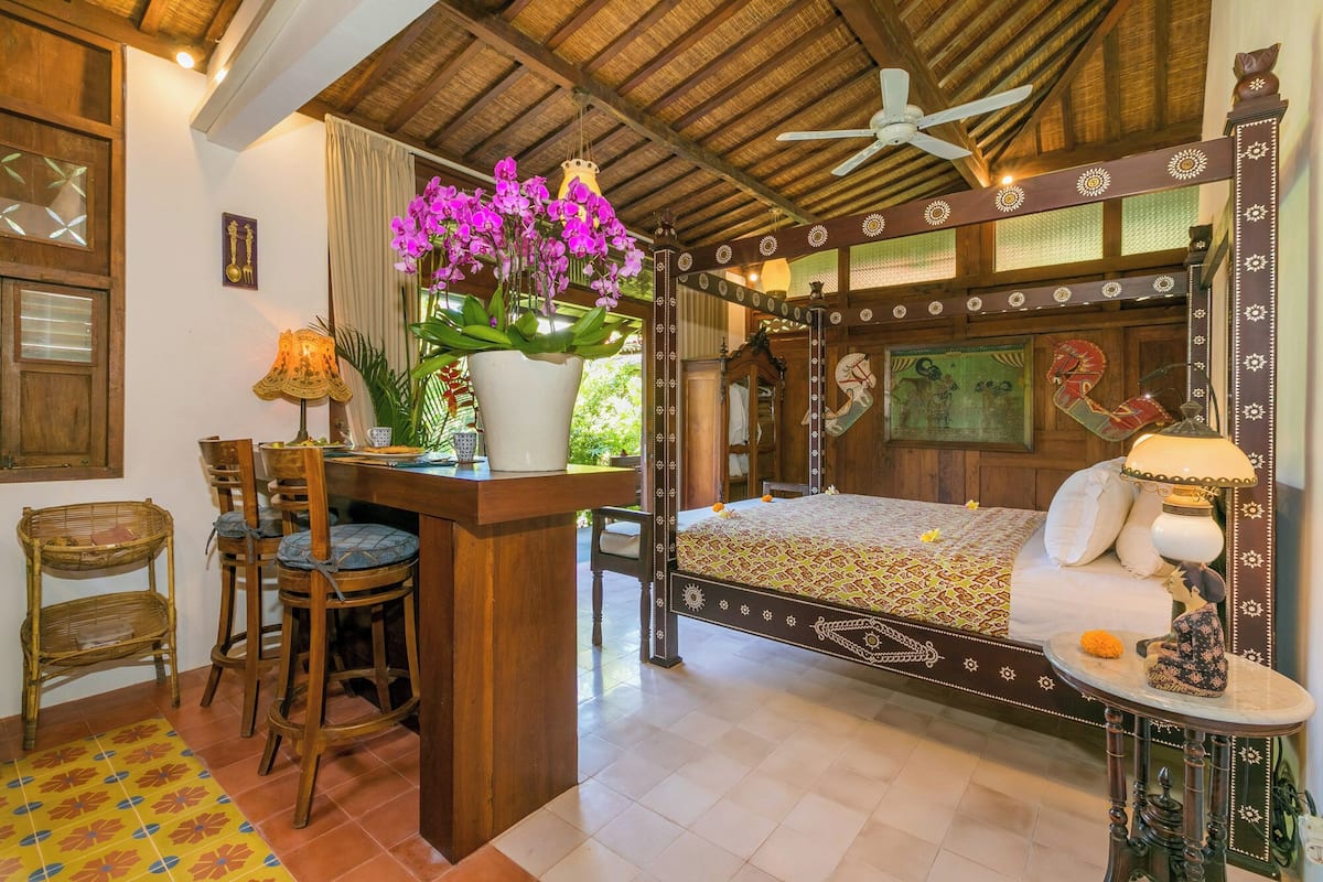 Una habitación con cama, escritorio, silla, lámpara y ventana con cortinas.