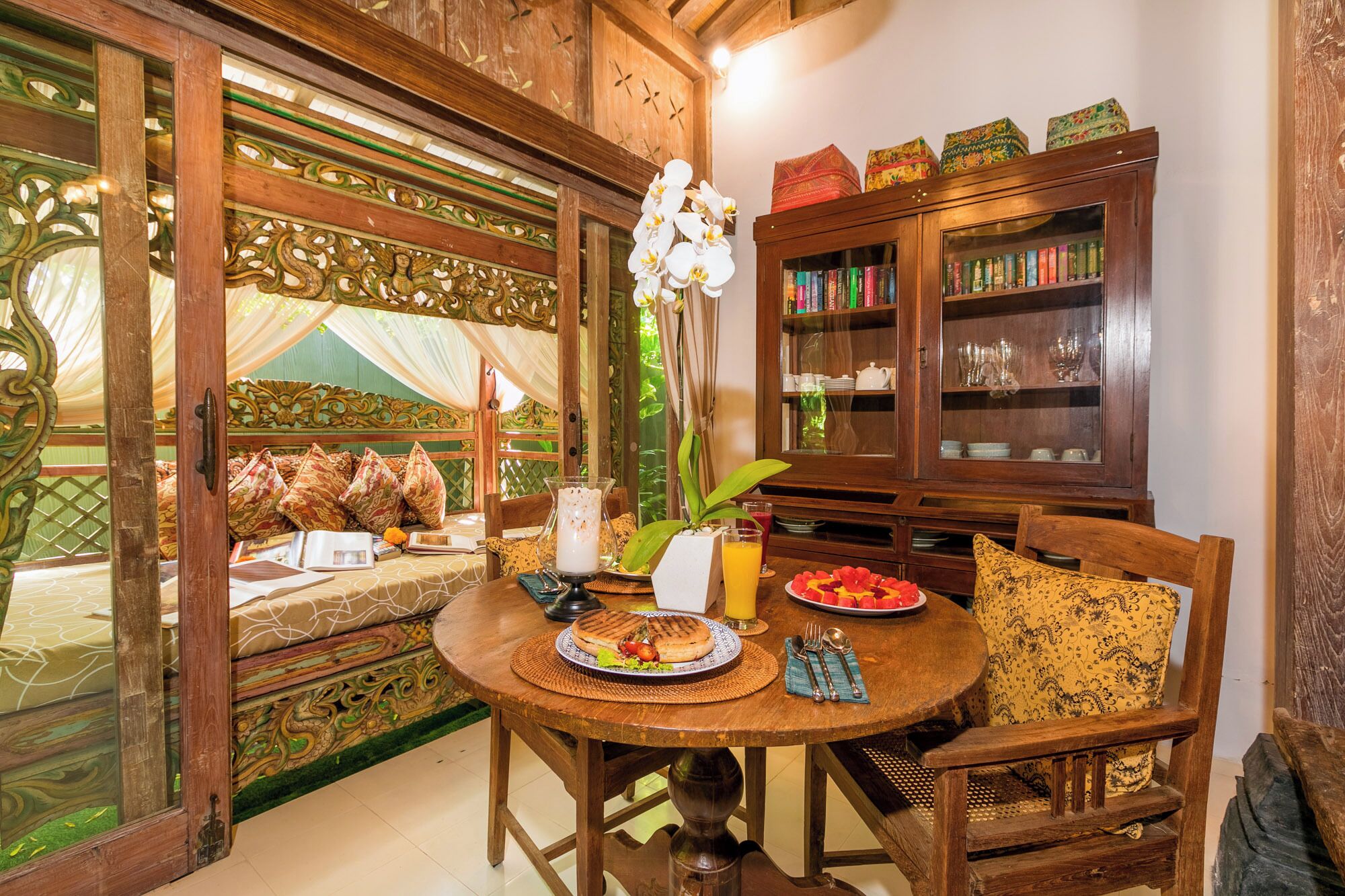 Un coin repas avec une table en bois, des chaises, une bibliothèque et une vue à travers une porte en bois.
