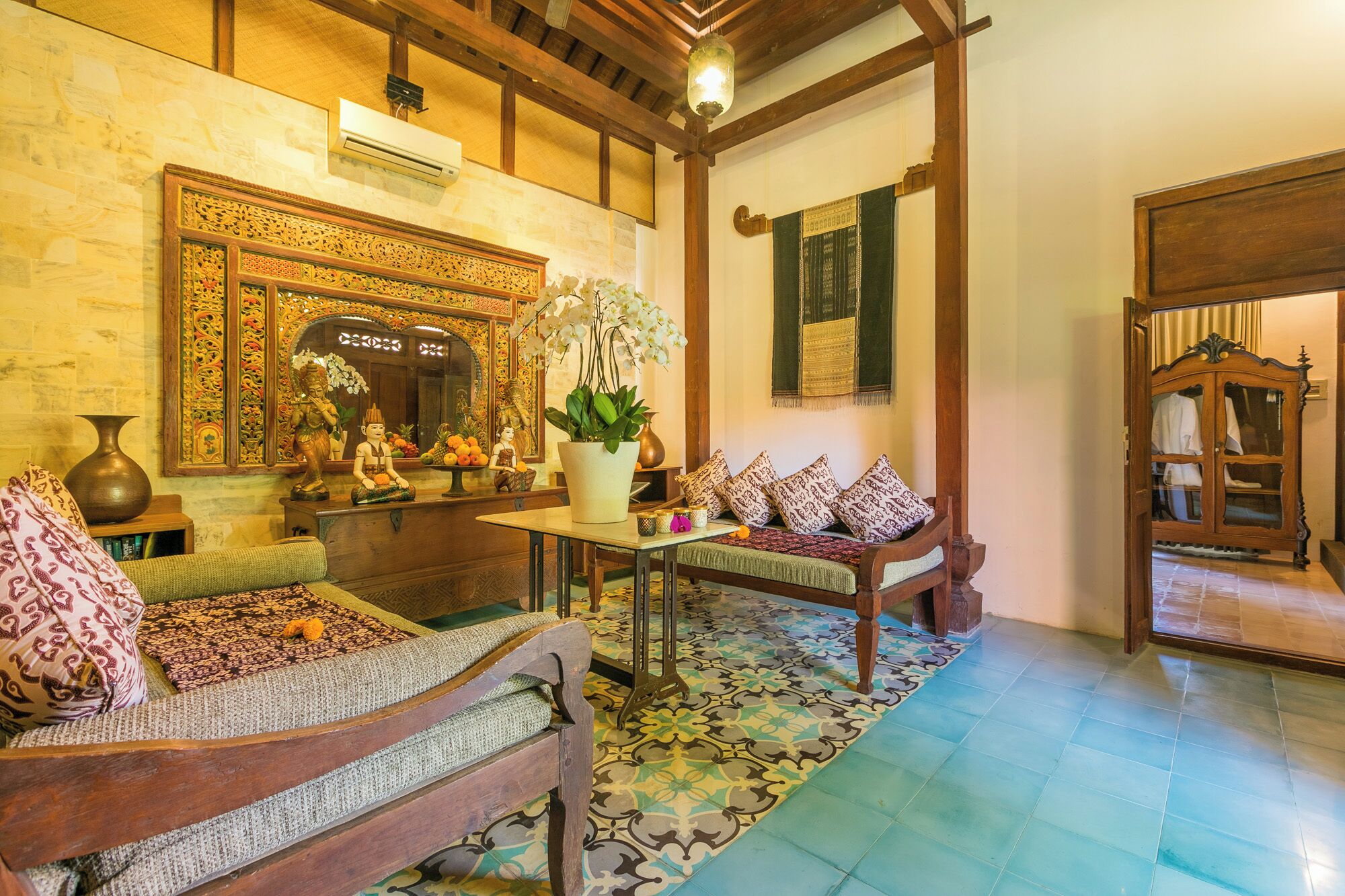 A traditional room with a wooden sofa, a small table, and a decorative mirror.