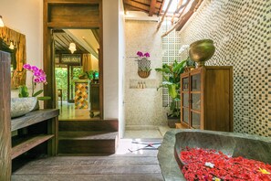 Un banco de madera, una fuente de piedra con flores y una pared de azulejos con un diseño a cuadros.