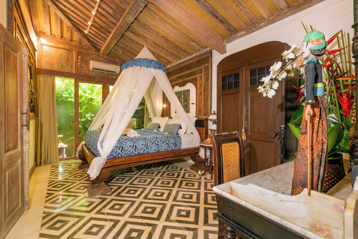Una habitación con cama, techo de madera y piso estampado.
