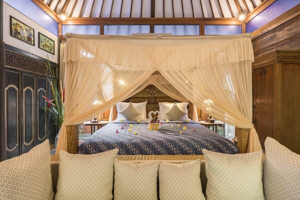 Un dormitorio con cama con dosel, cabecero de madera y almohadas decorativas.