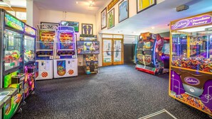 Un hall de hotel con varios juegos de arcade, incluyendo baloncesto y carreras, y un juego de fábrica de chocolate.