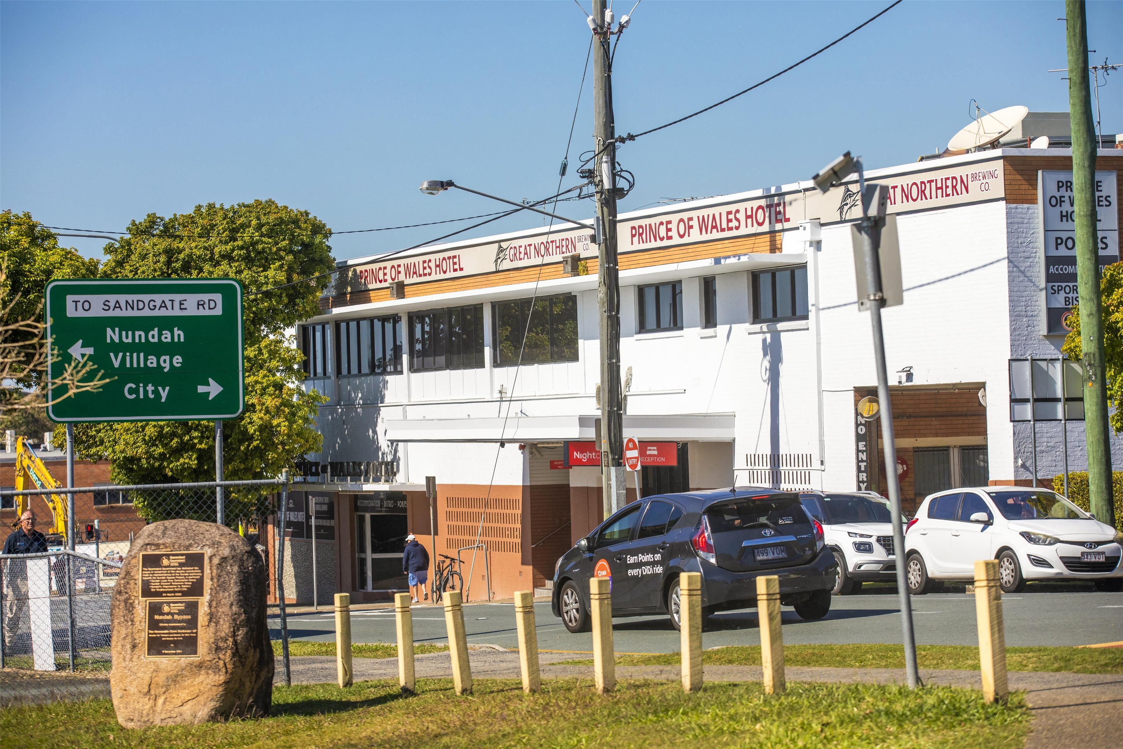 A hotel with signage for Sandgate Rd, Nundah Village, and City.