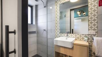 A modern bathroom with a glass shower enclosure, a white sink, and a wooden vanity.