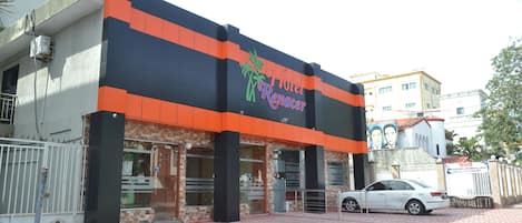 A hotel with a modern facade, featuring a prominent logo and a gated entrance.