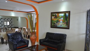 Un interno moderno con due divani in pelle nera, un tavolino in vetro e un'area pranzo con tavoli e sedie.