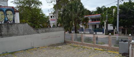 A paved parking area with a concrete wall and a metal fence.